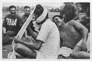 An Indian athlete puts his turban on, entertaining the Italian athletes around him